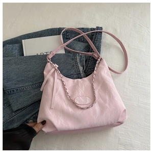 Detailed texture of pink hobo bag with silver chain on denim and arts book