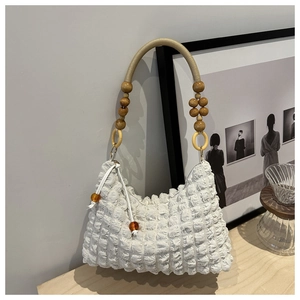 Détail du tissu à texture bulle blanche et poignée en perles de bois d'un sac à épaule