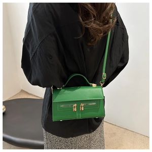 Sac bandoulière vert avec double fermeture éclair et cadenas dorés sur modèle