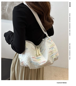 Detail view of white canvas hobo bag with colorful wave embroidery and adjustable strap
