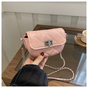 Détail du mini sac bandoulière matelassé rose avec chaîne argentée sur une table