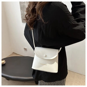 Detail of white glossy bucket bag featuring FASHION & BAGS lettering and shoulder strap
