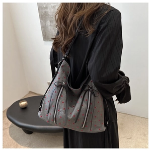 Detailansicht der grauen Canvas-Tasche mit roten Punkten und dekorativen schwarzen Schleifen