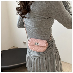 Détail d'un mini sac bandoulière rose matelassé avec chaîne argentée porté par un mannequin