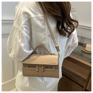 Sac à bandoulière beige avec double fermeture éclair et verrous dorés porté à l'épaule