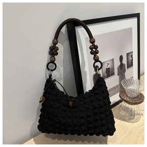 Détail du sac texturé gaufré noir avec sangle en perles de bois et tirette ambre