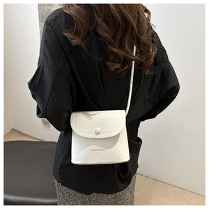 Rear view of a white minimalist leather crossbody bag with circular snap and fashion text