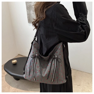 Detailed view of gray polka dot tote bag with black leather straps and zipper tassels