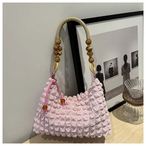 Détail du sac rose à texture popcorn avec poignée perlée et breloque en ambre