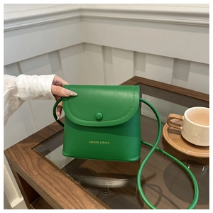 Detailed close-up of a vibrant green leather bucket bag with elegant gold brand lettering