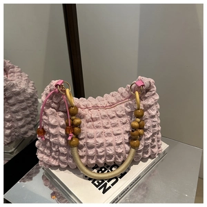 Détail d'un sac plissé rose avec des perles en bois et une poignée en corde tressée