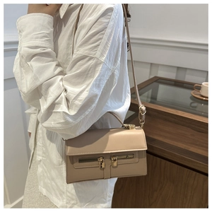 Détail du sac bandoulière beige vintage avec serrures dorées dans un intérieur élégant