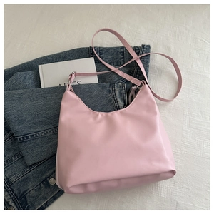 Detailed view of light pink hobo shoulder bag on textured white fabric background