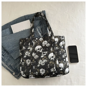 Detail of gothic tote bag with skull and floral print on white textured background