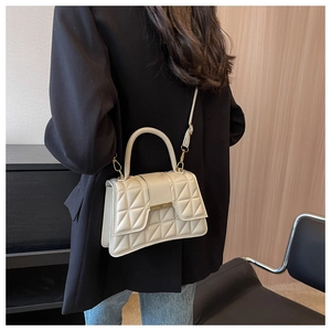 Dettaglio borsa a tracolla beige trapuntata con finiture dorate e manico rotondo chic