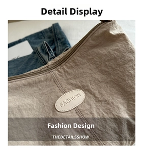 Detail of khaki pleated nylon crescent bag with leather fashion patch and metal zipper