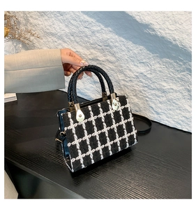 Detail of tweed checkered handbag showing black leather handle and gold hardware accents