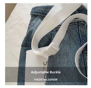 Detail of adjustable white strap with plastic buckle on a blue denim tote bag