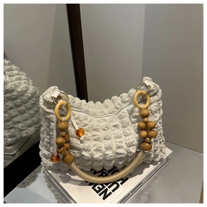 Détail du sac blanc à texture gaufrée avec poignée en perles de bois et zip à anneau métal