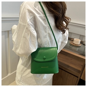 Detail view of grass green leather square bag with snap closure and adjustable strap