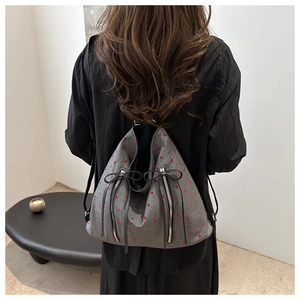Grey canvas backpack with red polka dots and bow detail shown on a model's back