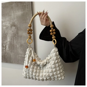 Détail du sac à bandoulière plissé blanc avec anse en perles de bois au style rétro chic