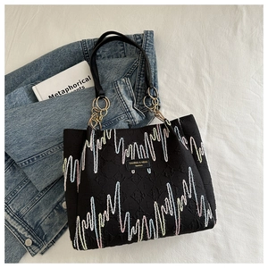 Détail du sac cabas noir avec tissu texturé, broderie colorée et logo CAHRES & HEKA