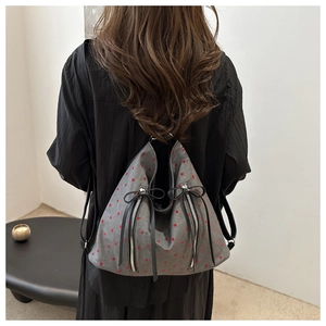 Detail eines grauen Rucksacks mit roten Punkten und vertikalen Doppel-Reißverschlusstaschen
