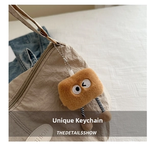 Close-up of creative brown plush charm with cartoon eyes on a beige pleated tote bag