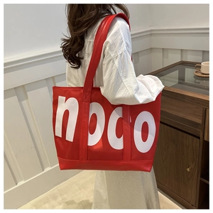 Close-up of a large red tote bag with white noco lettering on a wide shoulder strap