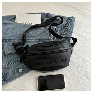 Detail of black leather sling bag with letter embroidery and adjustable nylon strap