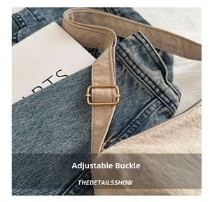 Detail shot of the golden adjustable buckle and textured beige fabric on a tote bag