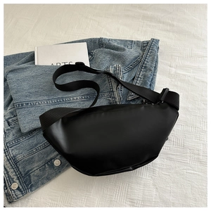 Flat lay of a minimalist black PU leather waist bag on denim and white bedding