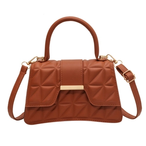 Bolso bandolera acolchado marrón con asa superior y hebilla dorada en fondo blanco