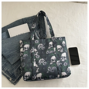 Detail of skull and floral print tote bag with a front pocket on white fabric background