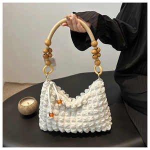 Détail du sac blanc en seersucker avec anse en perles de bois et breloque orange
