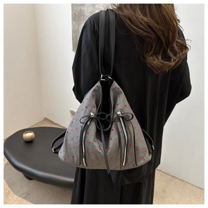 Detail of grey canvas tote bag with red polka dots and decorative zippers on model
