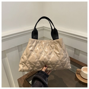 Détail d'un sac cabas matelassé beige avec anses noires et coutures en losange