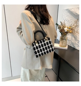 Side view of a vintage black and white plaid tweed small square bag with woven handle