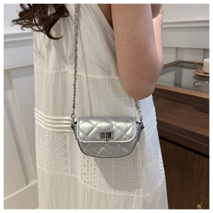 Mini sac bandoulière argenté à matelassage et chaîne, porté par un mannequin en intérieur