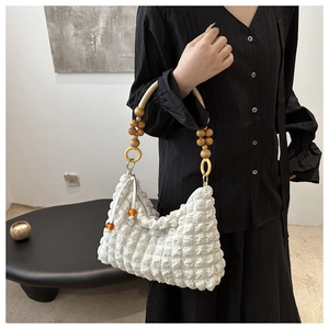 Détail du sac plissé blanc avec poignée en perles de bois et breloques ambre au zip