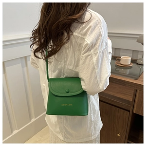 Grass green minimalist square crossbody bag with gold text detail worn by a model