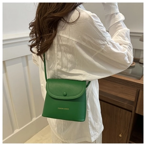 Detailed view of a green mini bucket bag worn by a model in a casual home setting