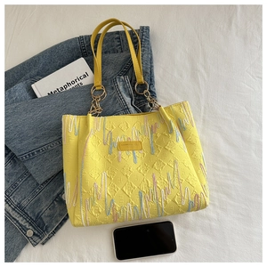 Gros plan d'un sac cabas jaune avec texture matelassée et broderie ondulée