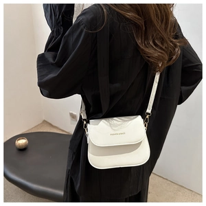 Detailed back view of a white leather saddle bag with gold logo on black dress