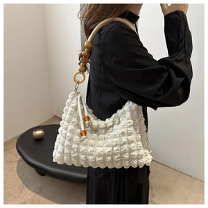 Détail du sac blanc à texture gaufrée avec bandoulière en perles de bois naturel