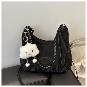 Macro shot of black pleated crescent bag with metal chain and plush cloud charm
