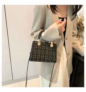 Classic black and gold tweed handbag with woven handle and gold hardware on model