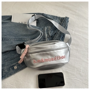 Close-up of metallic silver canvas fanny pack with pink embroidery and nylon strap details