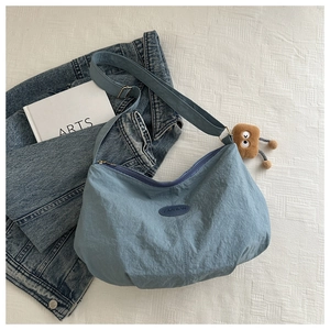 Detail of light blue shoulder bag with FASHION patch and brown plush toy accessory